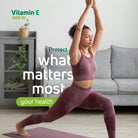 Woman stretching at home with Vitamin E 400 IU lifestyle message for daily health support.